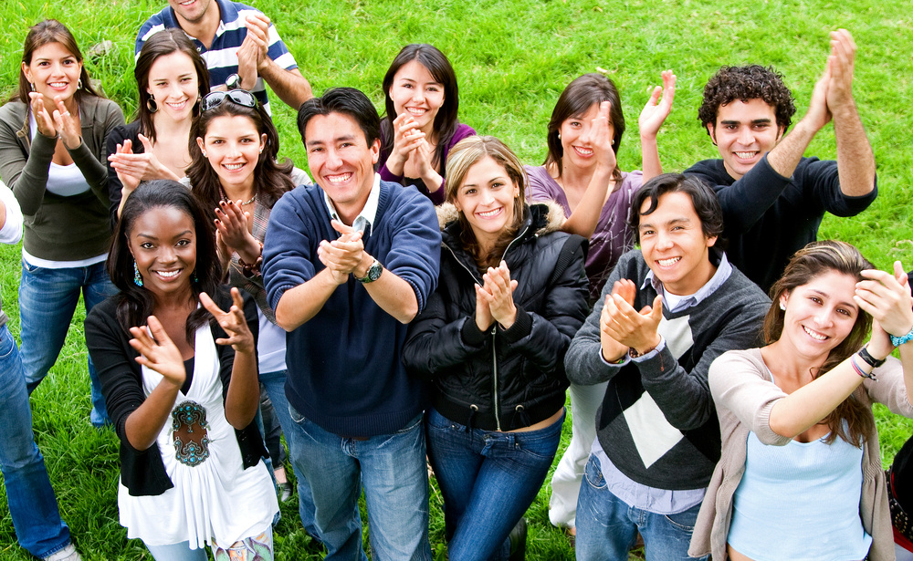 happy group of friends smiling and clapping outdoors